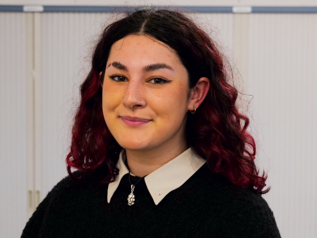 Photo of Mia, white collared shirt and black jumper.