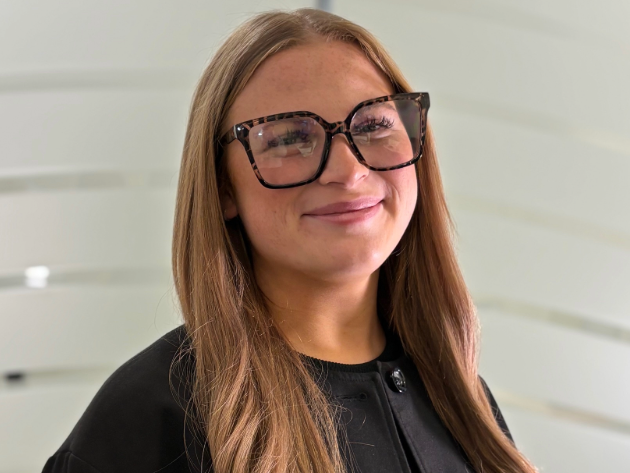 Photo of Ruby, wearing dark rimmed glasses, black top.