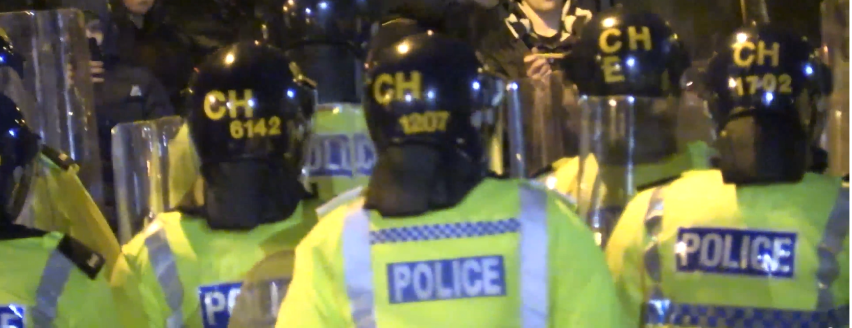 Photograph of several police officers in portective equipment including helmets and fluorescent yellow jackets