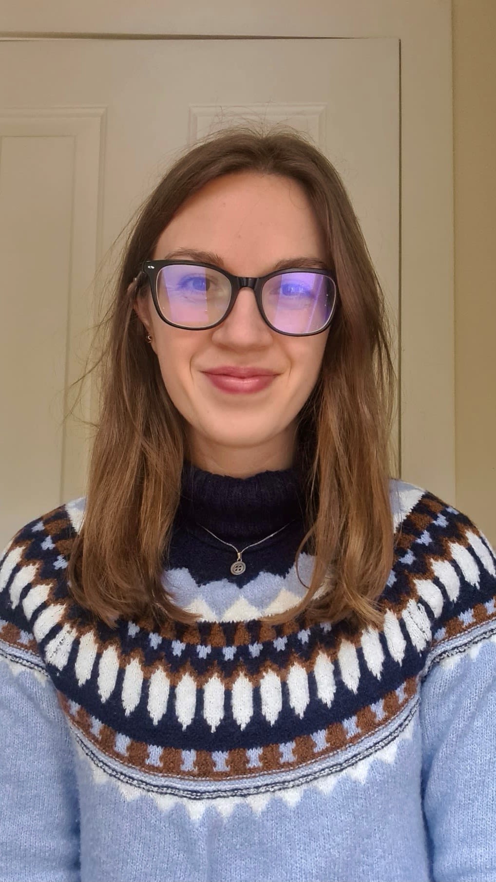 Image (headshot) of CPS employee with medium length brown hair, wearing glasses and wearing a blue patterned jumper..