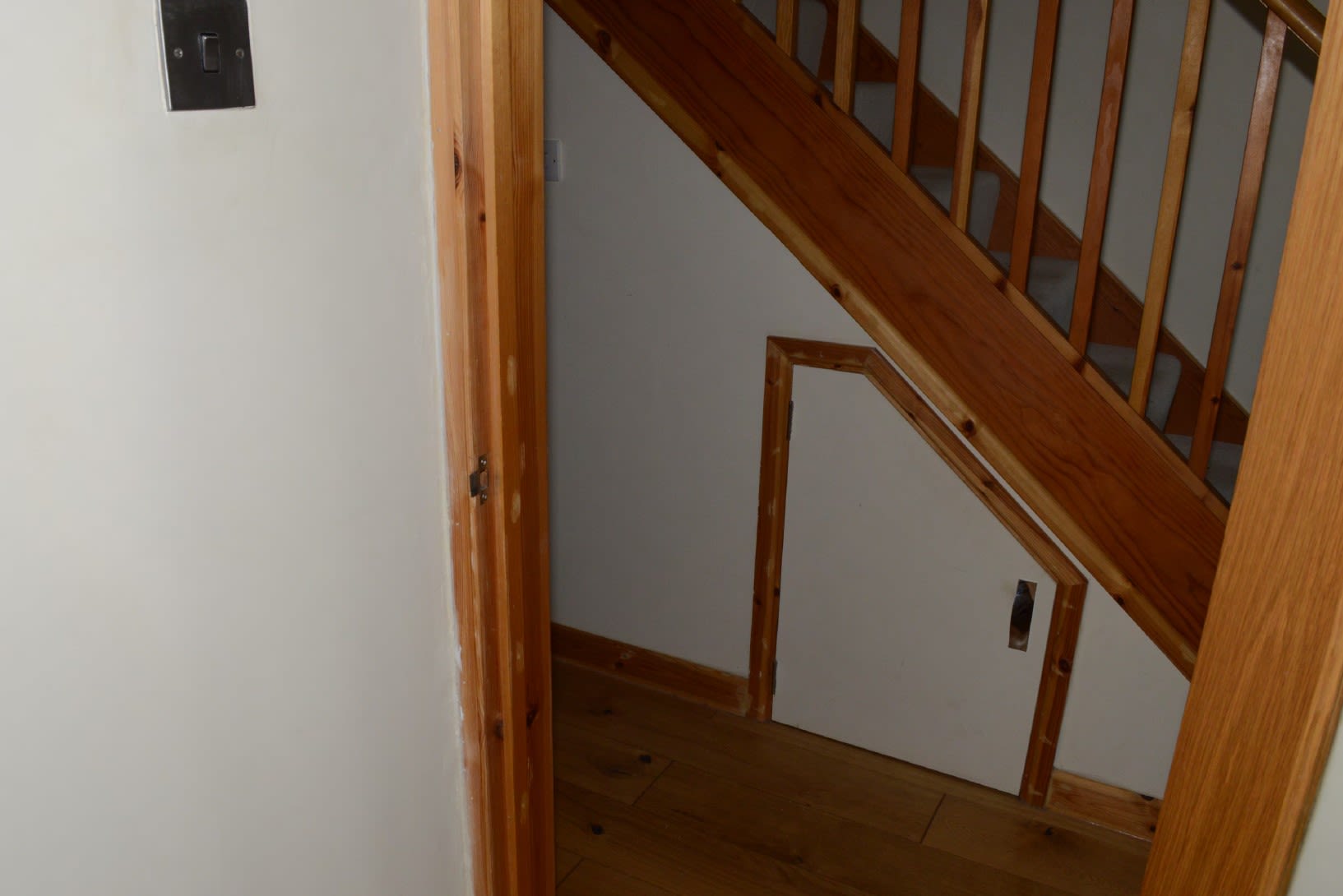 An image of a staircase and a small wooden cupboard benath it