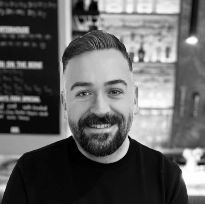 Head and shoulder photo of James in black and white. James had styled combed back short hair with a beard.