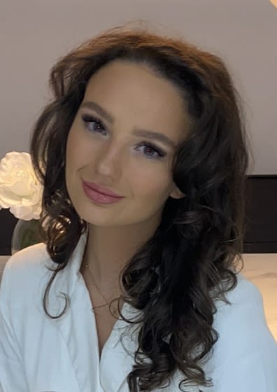 Head and shoulders photo of CPS employee Ashleigh, curled long brunette hair and wearing a white blouse.