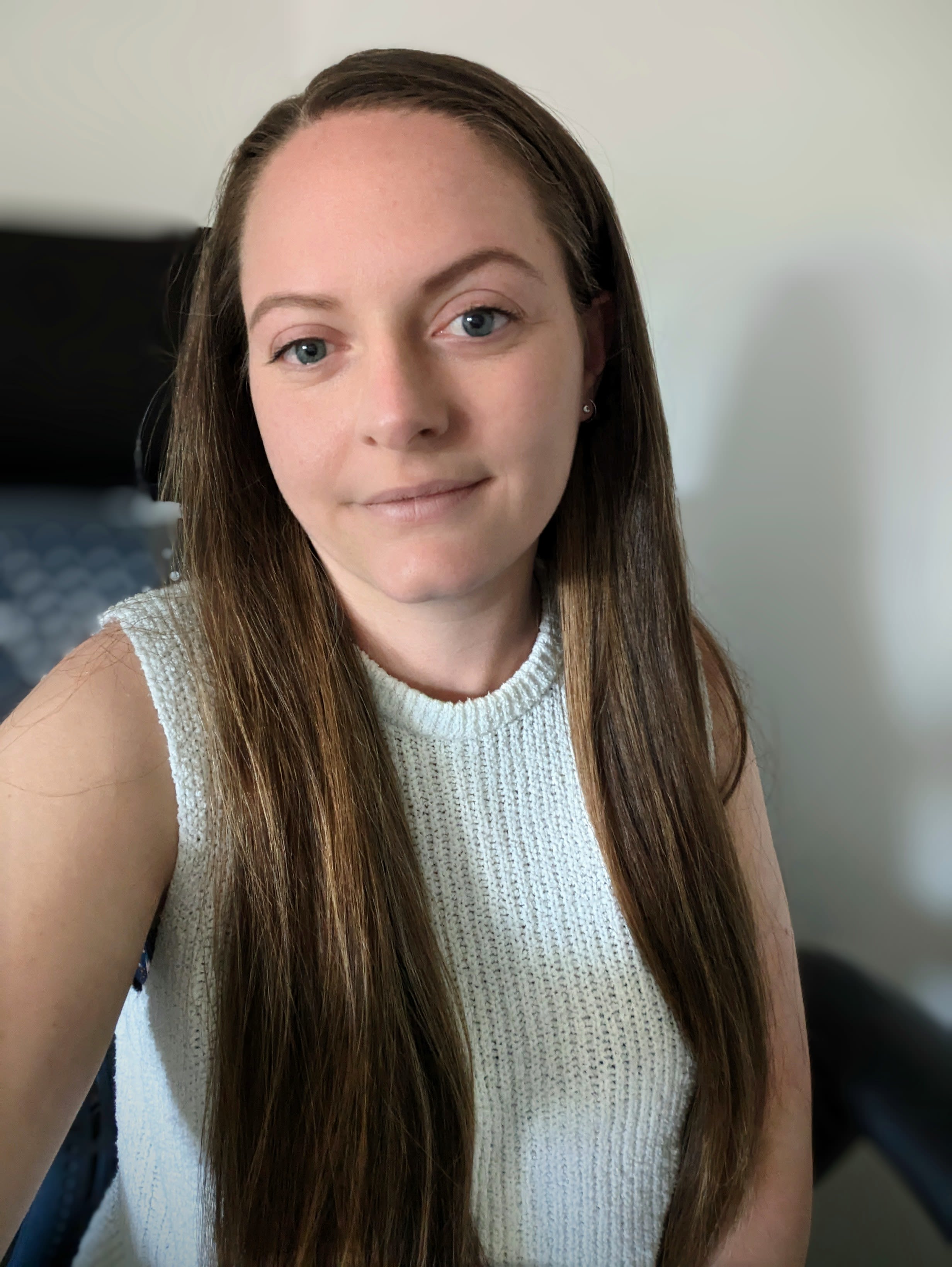 Head and shoulders photo of CPS employee, Jasmin. Very long straight hair, mid brown in colour. Wearing a knitted white top.