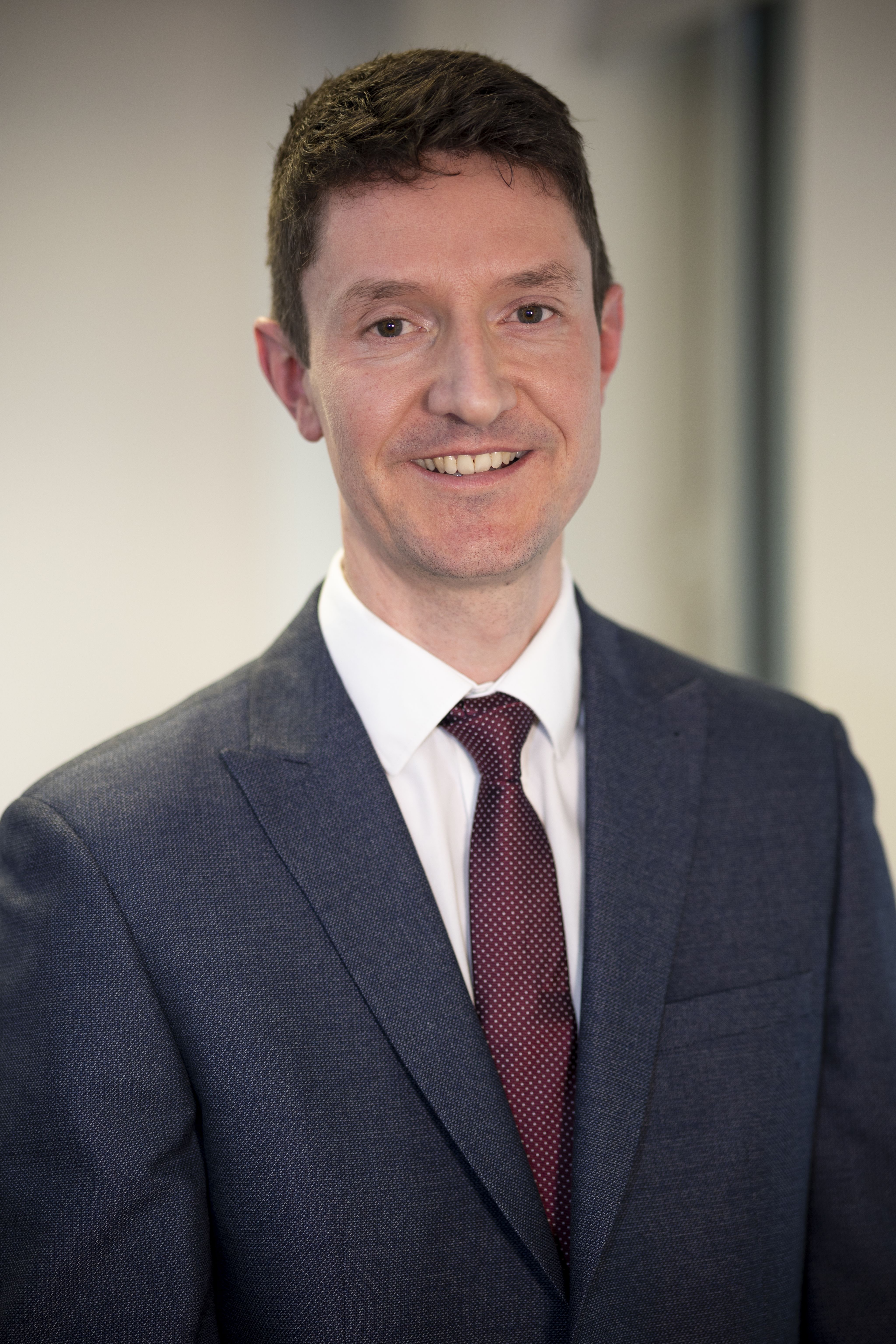 Head and shoulders photo of CPS employee Matt, Legal Manager. Short brown hair, wearing a dark suit with white shirt and burgundy tie.