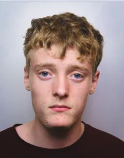 Jagger Strang, a 18 year old man with blonde hair and blue eyes, wearing a black t shirt on a grey background