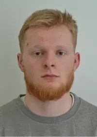 Jordan Richardson, a white man in his early twenties with ginger hair and a beard. He is wearing a grey jumper