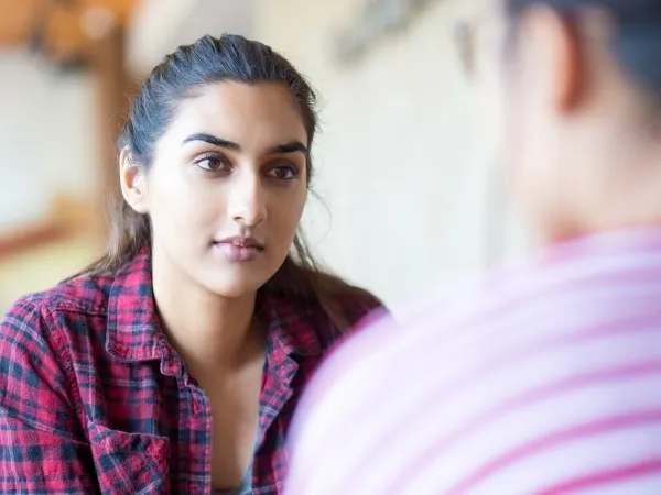 A young woman, seen over the shoulder of a young man, presumably her client. She looks calm, confident and reassuring.