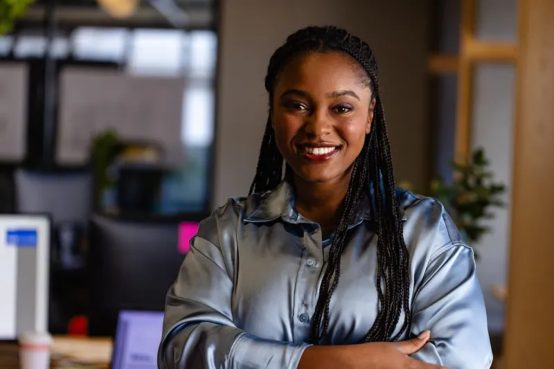 A young. smiling confident-looking Black woman in an office environment